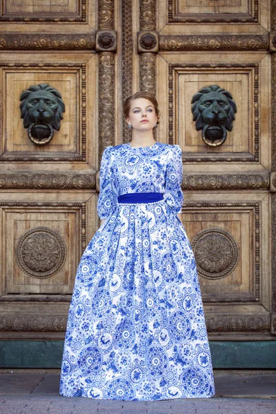 Menina loira bonita em vestido azul posando contra um fundo — Fotografia de Stock