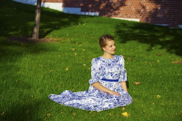 Menina loira bonita em vestido azul posando contra um fundo — Fotografia de Stock