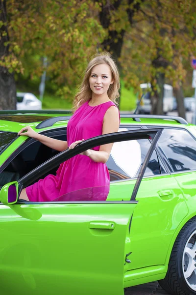 Portrait of a beautiful blonde woman and green sports car — Stock Photo, Image