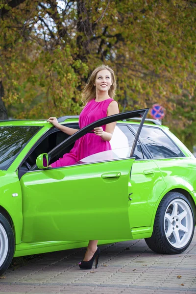 Portrait of a beautiful blonde woman and green sports car — Stock Photo, Image