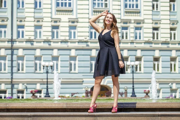 Unga vackra kvinnan i svart klänning poserar utomhus i soligt vi — Stockfoto