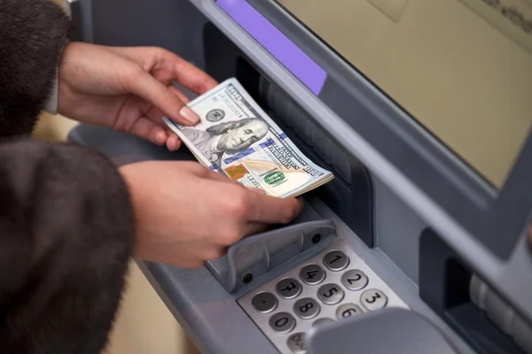 Woman hand showing dollar banknotes in front of the atm — Stock Photo, Image