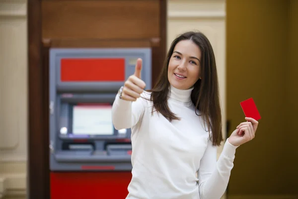 Молодая счастливая брюнетка женщина снимает деньги с кредитной карты в — стоковое фото