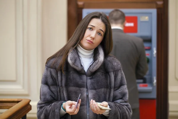 Mano de mujer mostrando billetes de dólar frente al cajero automático — Foto de Stock