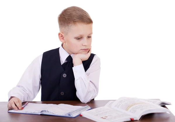 Кавказский школьник за своим столом на белом фоне с копиями — стоковое фото