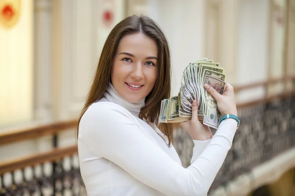 Morena feminina segurando e mostrando dólares — Fotografia de Stock