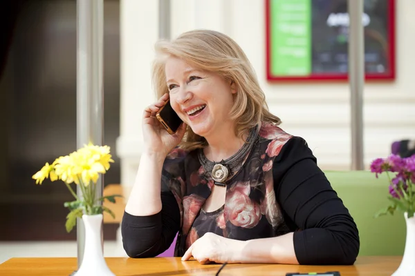 Reife schöne Frau telefoniert im Sitzen mit einem Handy — Stockfoto