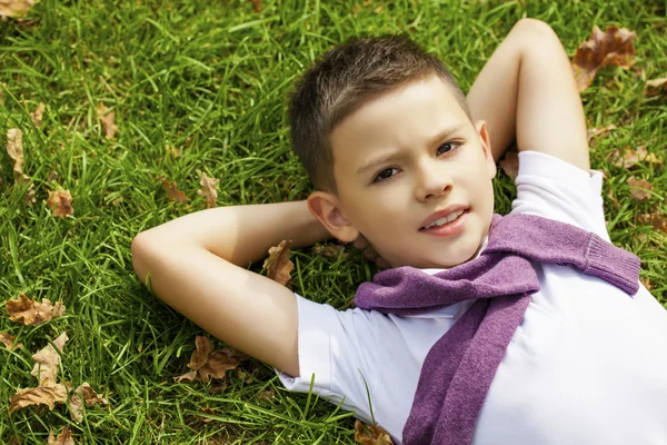 Brunetka chłopiec na trawie w parku — Zdjęcie stockowe