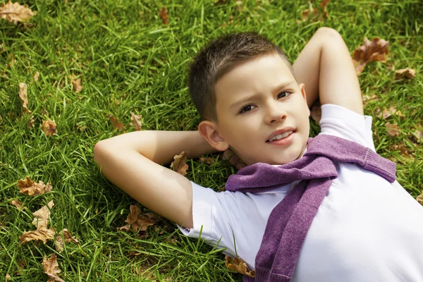 Brünetten kleinen Jungen auf dem Gras im Park liegen — Stockfoto