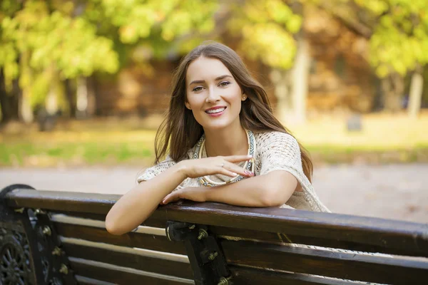 Sonbahar parkta bir bankta oturan güzel kız — Stok fotoğraf