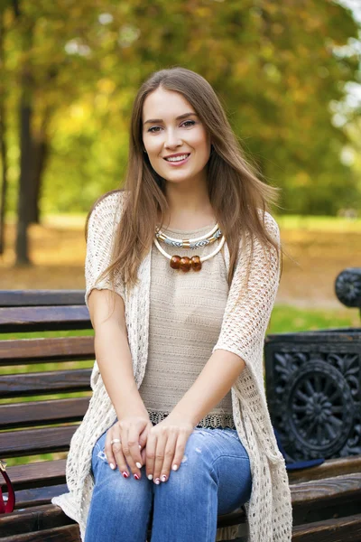 Hermosa chica descansando en un banco en el parque de otoño — Foto de Stock