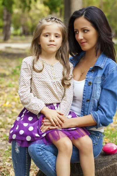 Красивая маленькая девочка и счастливая мама в осеннем парке — стоковое фото