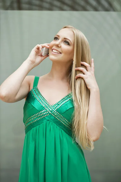 Menina bonita nova no vestido verde falando no telefone celular — Fotografia de Stock