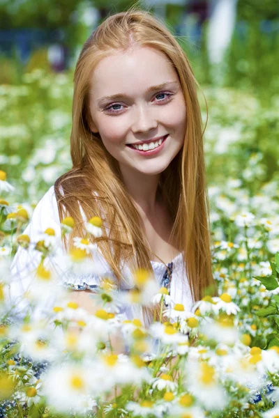 Junge Frau sitzt in einem Kamillenfeld — Stockfoto