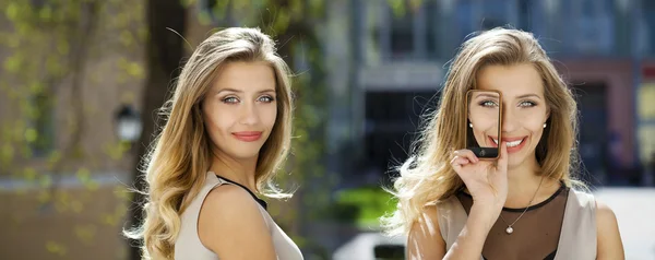 Colagem, duas mulheres cobre sua tela de rosto telefone inteligente — Fotografia de Stock