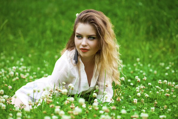 Young blonde woman on green meadow 