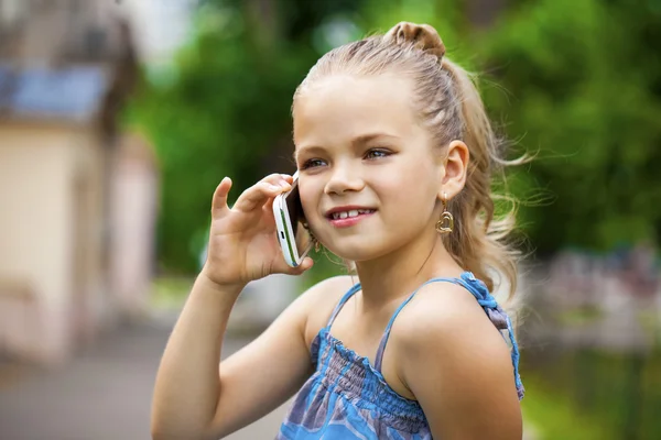 Kleines Mädchen telefoniert mit Handy gegen Grün des Parks in Summen — Stockfoto