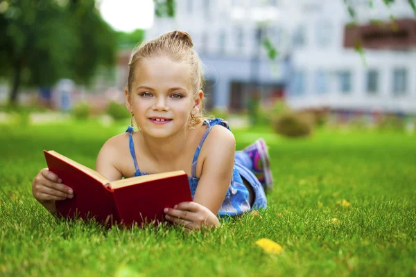 Adorable cute little girl reading book outside on grass — Stock Photo, Image