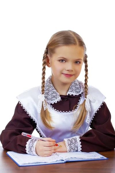 Jonge mooie schoolmeisje zitten aan een bureau — Stockfoto