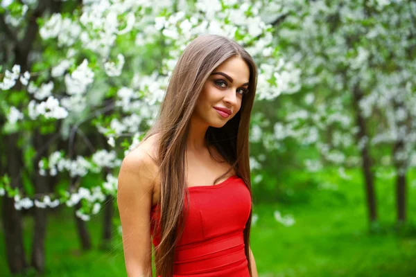 Jovem feliz em vestido vermelho contra o fundo flo primavera — Fotografia de Stock