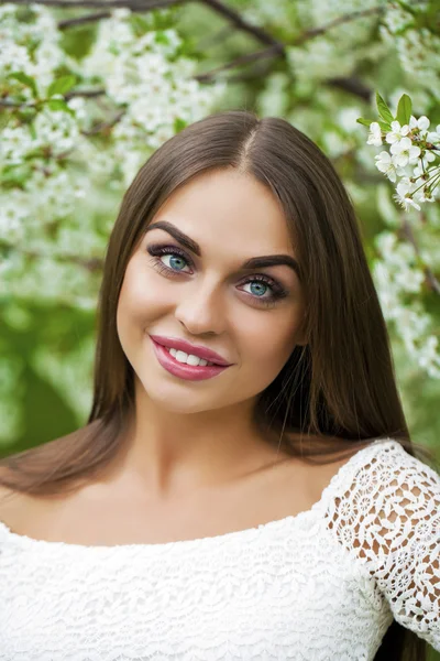 Happy young woman in white dress against the background spring f — Stock Photo, Image