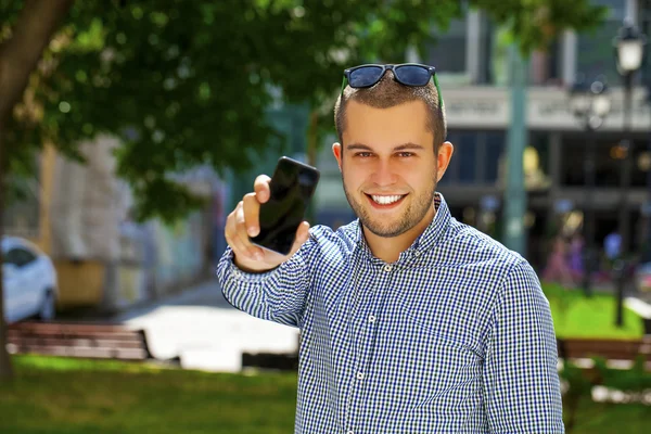 Un jeune homme montre un écran de téléphone portable — Photo