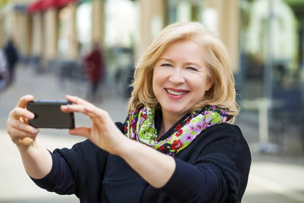 Glücklich reifen schönen blonden Frau auf einem Handy fotografiert — Stockfoto