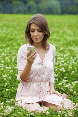 Genç bayan telefonda bir mesaj okuyor. 