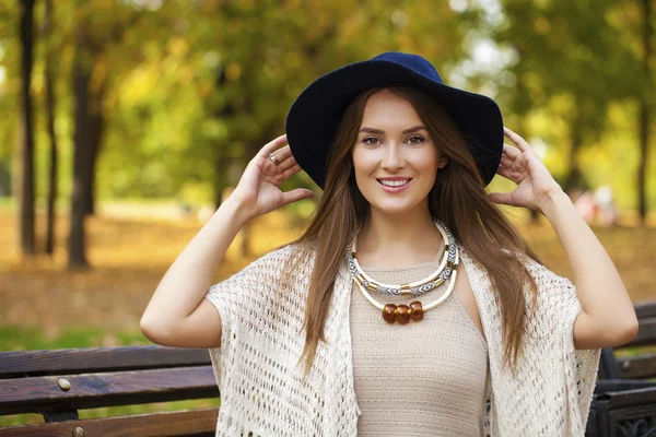 Mooi meisje rusten op een bankje in de herfst park — Stockfoto