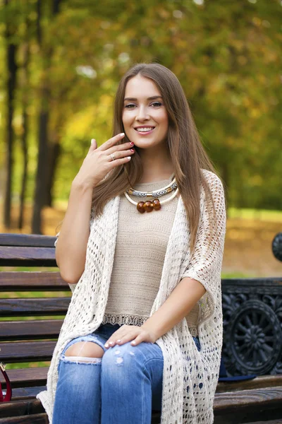 Schönes Mädchen, das auf einer Bank im herbstlichen Park ruht — Stockfoto