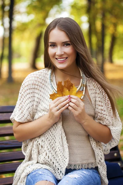 Vacker flicka vilar på en bänk i parken höst — Stockfoto