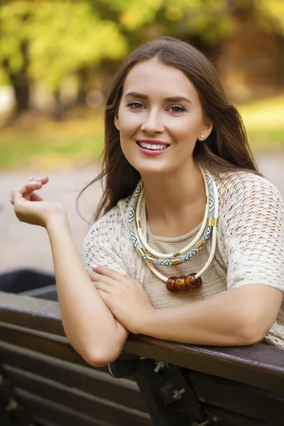 Sonbahar parkta bir bankta oturan güzel kız — Stok fotoğraf