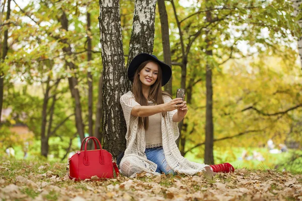 Молода красива жінка фотографує себе на мобільному телефоні — стокове фото