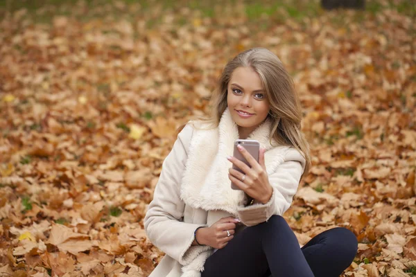 Vacker ung kvinna läser ett meddelande på telefonen — Stockfoto