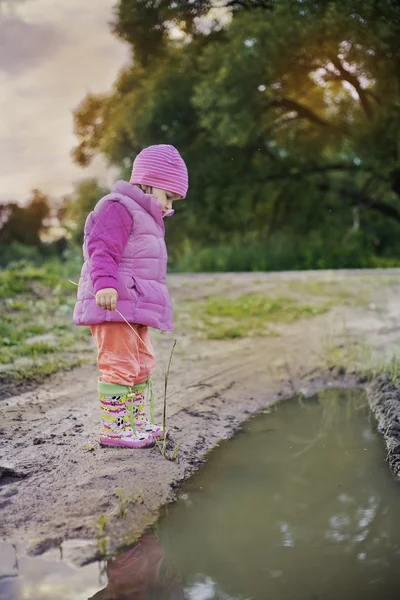 Cute little girl near a puddle — Stock Photo, Image