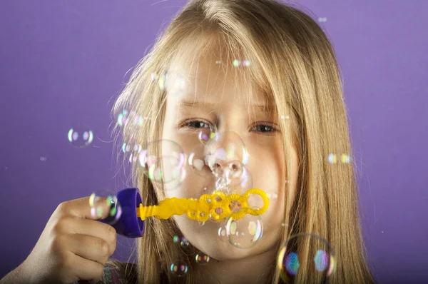 Маленька дівчинка дме мильні бульбашки — стокове фото