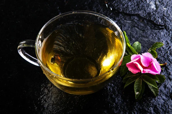 Травяной чай в чашке и розовый цветок — стоковое фото