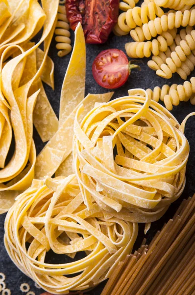 Dry italian different pasta with tomatoes — Free Stock Photo