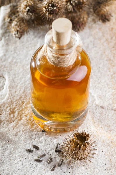 Bottle with burdock oil and dry flowers — Stock Photo, Image