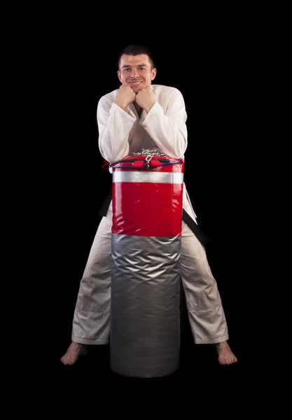 Uomo in kimono con sacco da boxe — Foto Stock