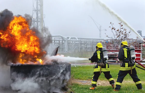 Deux pompiers combattant un grand feu de flamme . — Photo