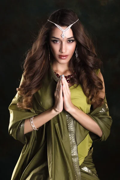 Mooie vrouw in groene Indiase sari en juwelen op kleurrijke ba — Stockfoto