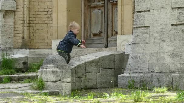 Pojke spelar utomhus. Hoppar från stegen — Stockvideo