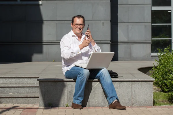 Homem adulto com computador e telefone celular — Fotografia de Stock