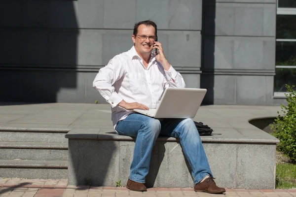 Homem adulto com computador e telefone celular — Fotografia de Stock