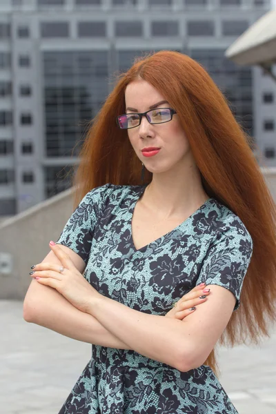 Roodharige vrouw op de achtergrond van kantoorgebouw — Stockfoto