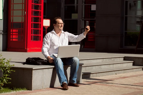 Biznes człowiek za pomocą telefonu komórkowego, które angielski klasyczny czerwony telefon bo — Zdjęcie stockowe