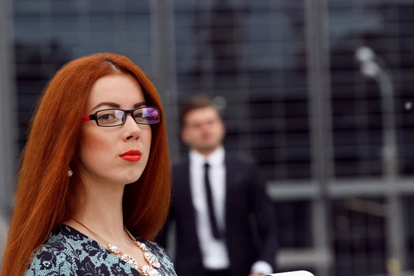 Roodharige vrouw poseren op springen zakenman achtergrond — Stockfoto