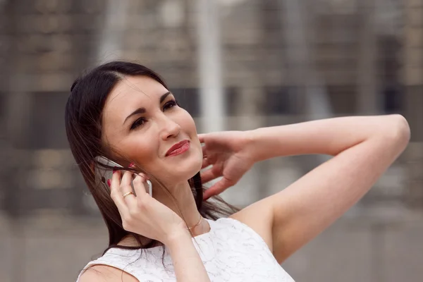 Mooie vrouw met behulp van mobiele telefoon op stedelijke achtergrond — Stockfoto