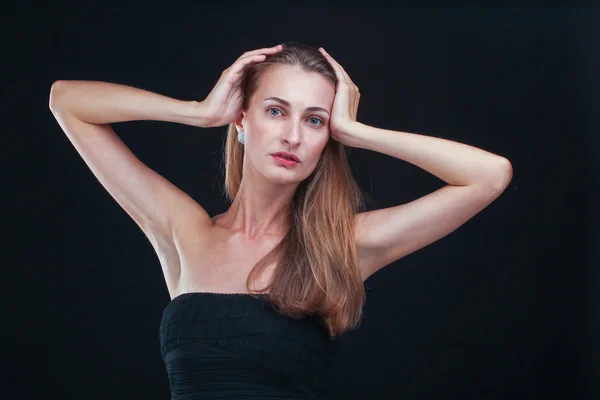 Jolie femme tenant la tête dans les mains debout contre backgr noir — Photo